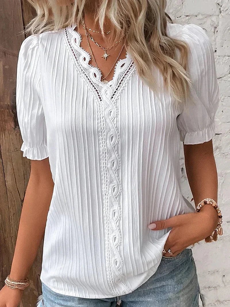 Woman wearing the Bea elegant blouse with delicate lace accents and short puff sleeves in a light, airy fabric