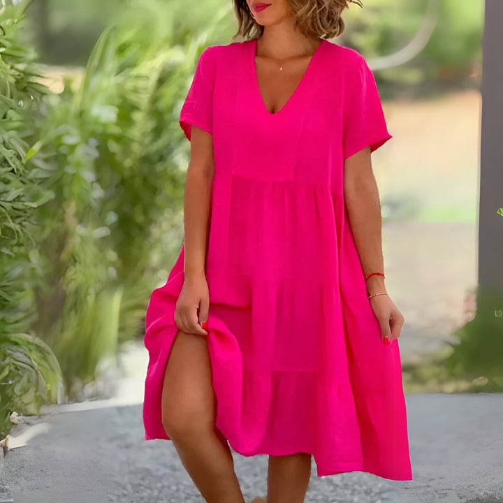 Woman wearing the Beatrice flowy V-neck dress in pink, showcasing the flattering silhouette and soft draping