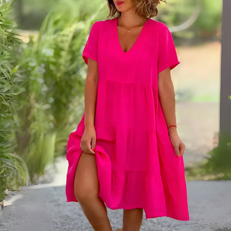 Woman wearing the Beatrice flowy V-neck dress in pink, showcasing the flattering silhouette and soft draping