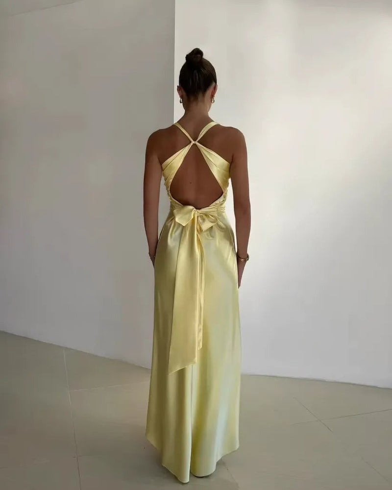 Close-up of the open bow-back detail on a yellow satin-finish maxi dress