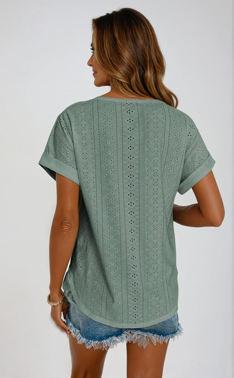 Front view of a woman in a light blue eyelet top styled with high-waisted jeans