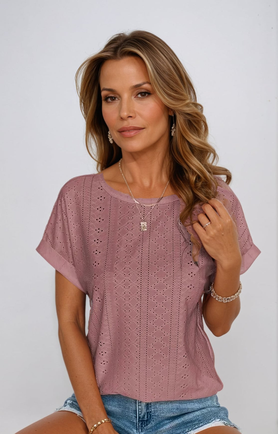 Woman in a pink casual eyelet top paired with a white skirt in an outdoor setting