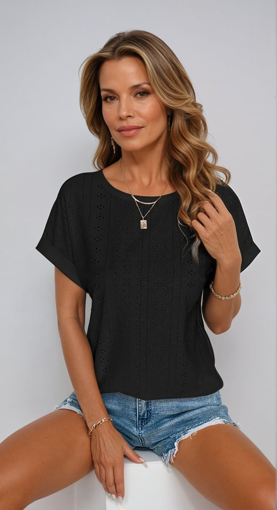 Woman wearing a black eyelet top with relaxed fit, shown from the front