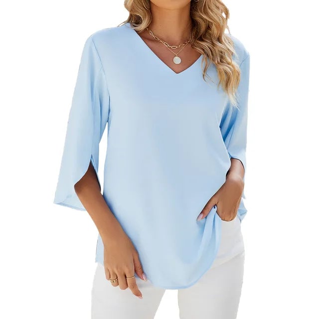 Woman wearing a light blue V-neck blouse with a relaxed fit, styled casually for everyday wear