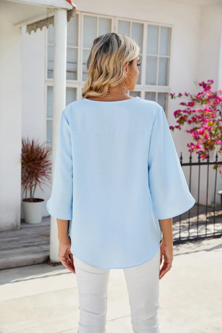 Woman tucking a white V-neck blouse into a midi skirt for a polished, put-together look