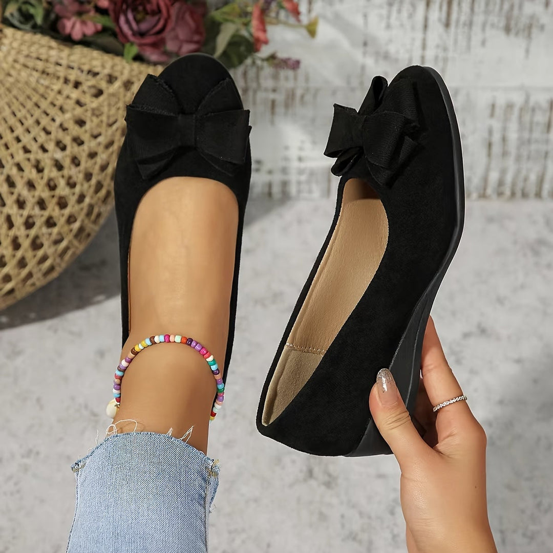 Black suede-look ballet flat with structured bow detail at the round toe, side view