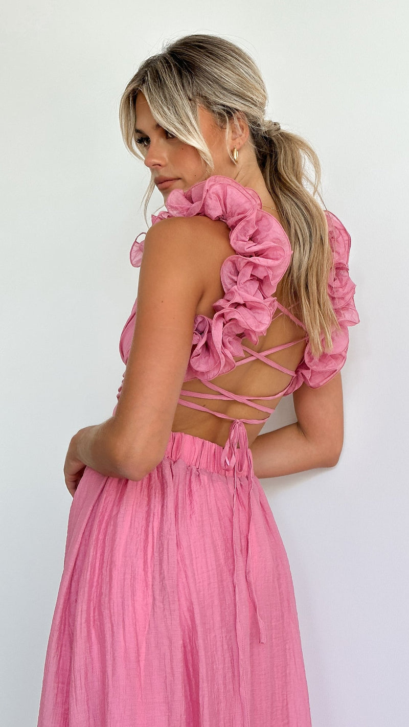 Woman wearing the Belle pink wedding guest dress with a flowing skirt and graceful neckline, front view
