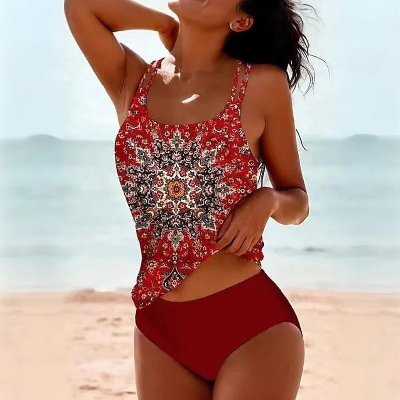 Model wearing the printed tankini in a beach setting, showing the flattering high-rise bottom and wireless top