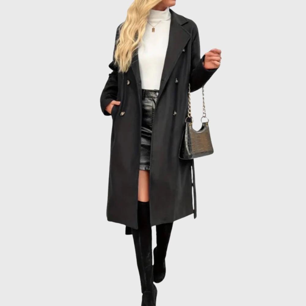 Close-up detail of black longline trench coat showing insulated fabric, belt, and structured lapels