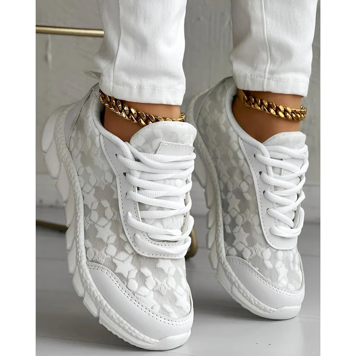 White chunky platform sneakers with a floral lace overlay upper and lace-up closure, front view