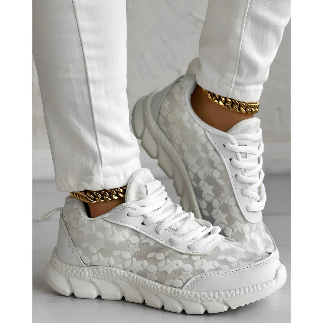 Overhead flat-lay of white floral lace overlay sneakers on a clean neutral background