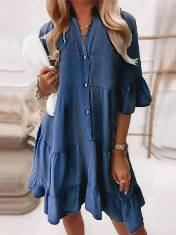 Model wearing the Billie tiered ruffle mini dress in navy blue styled with tan sandals and gold jewelry
