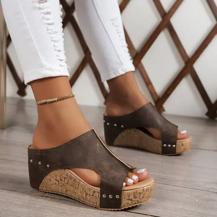 Woman wearing black Birdie orthopedic sandals while walking on a light pavement surface