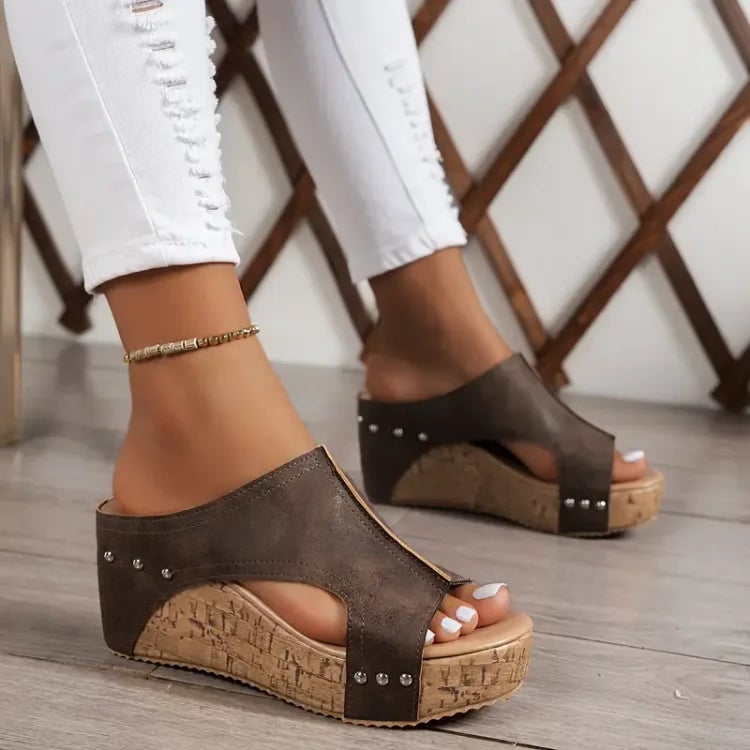 Woman wearing black Birdie orthopedic sandals while walking on a light pavement surface