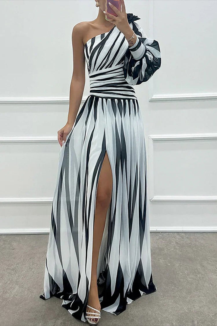 Woman wearing a white striped one-shoulder maxi dress with a defined waist and flowing pleated skirt