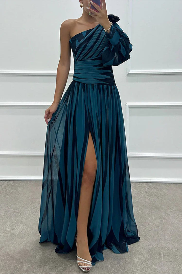 Full-length side view of a green striped one-shoulder maxi dress showing the pleated skirt movement