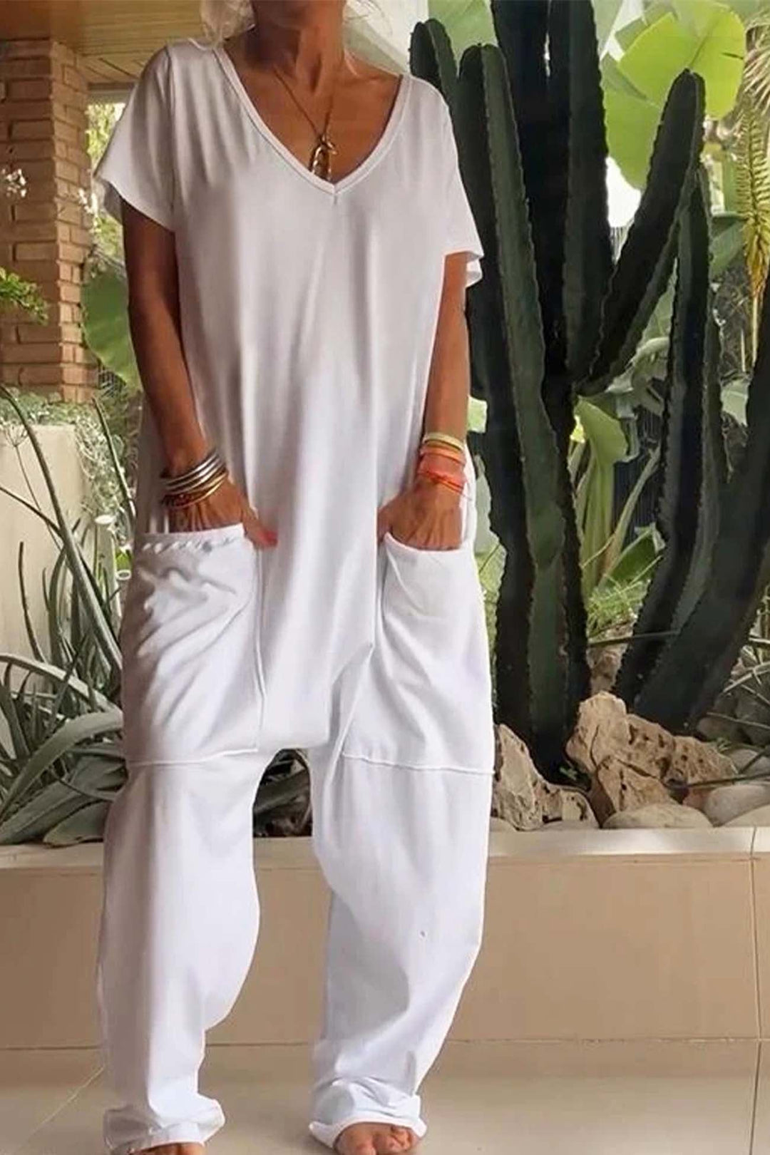 Woman styling the white V-neck jumpsuit with sandals for a casual everyday look