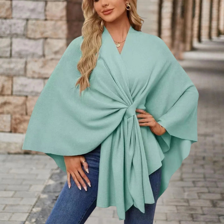 Model wearing a draped poncho layered over a dress for a refined look