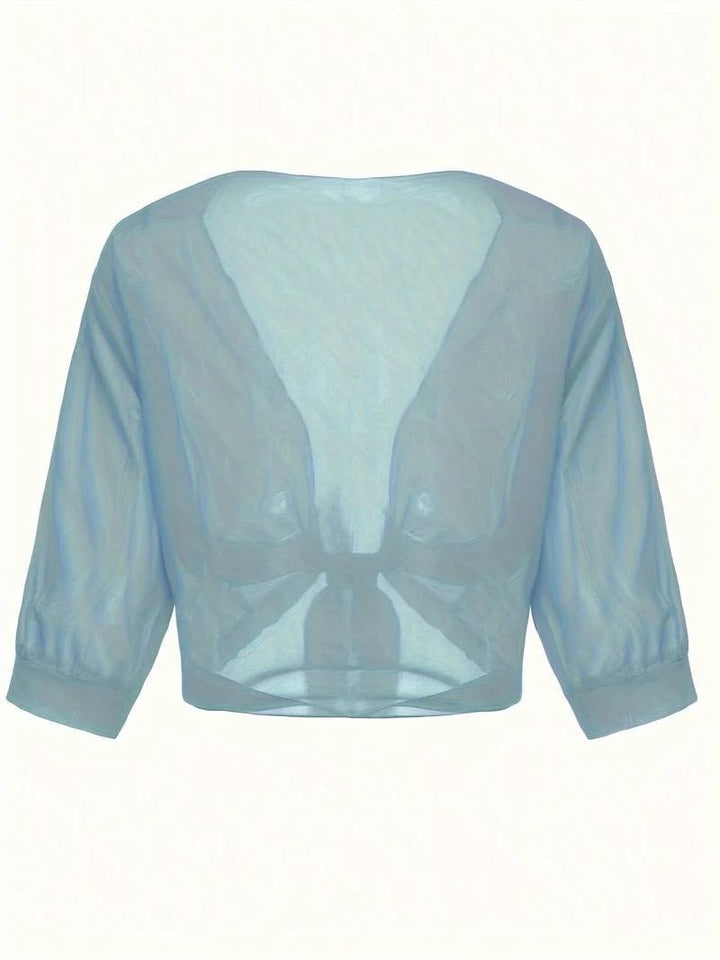 Woman in the Brisa open-front sheer blouse in emerald green with knotted hem