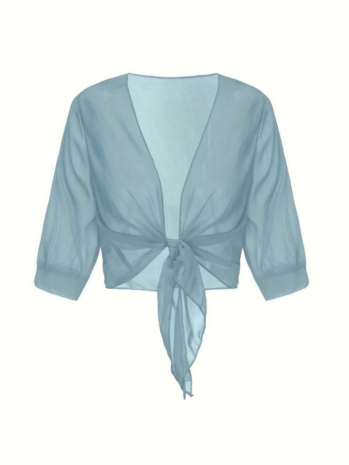 Front view of the Brisa tie front blouse in emerald styled over a neutral top