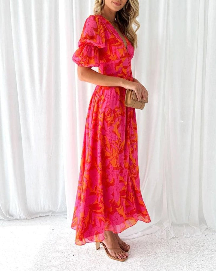 Close-up of the red-pink maxi dress showing the soft fabric drape and puff sleeve detail