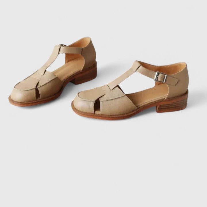 Pair of Brooke sandals in beige styled with a flowy midi dress for a polished daytime look