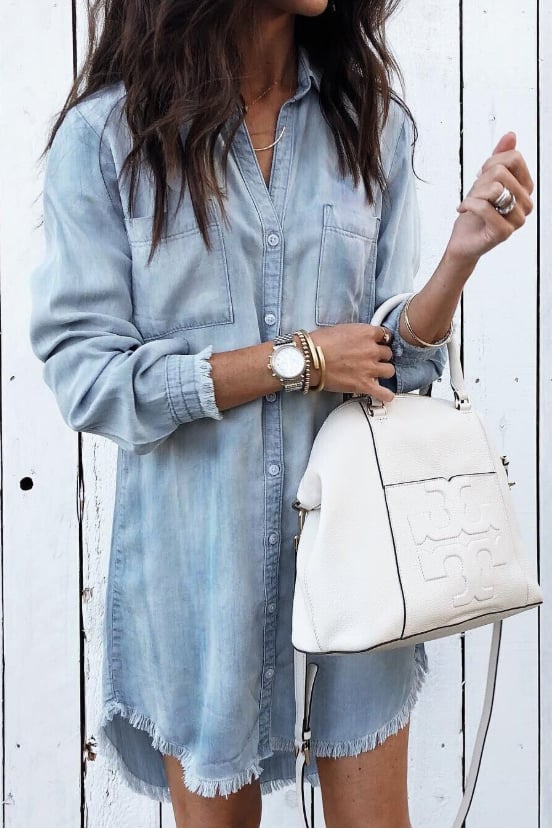 Woman wearing the Brooke washed denim shirt dress in blue with long sleeves and a raw frayed hem, styled casually