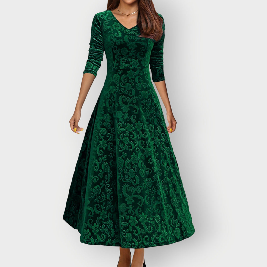 Woman in blue velvet midi dress posing at a festive evening event, three-quarter view