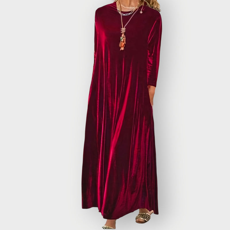 Model wearing a flowing burgundy velvet maxi dress with a flattering feminine silhouette