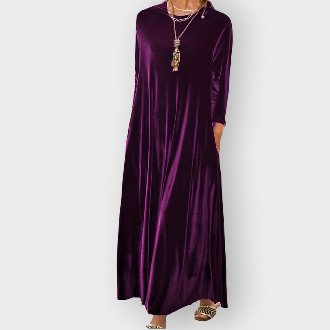 Side view of model in black velvet maxi dress highlighting the flowing skirt and body-skimming fit