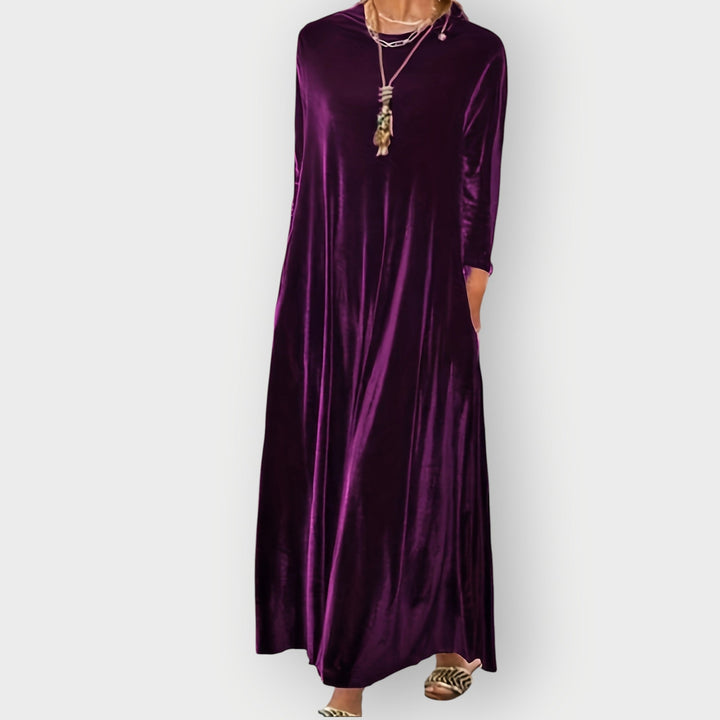 Side view of model in black velvet maxi dress highlighting the flowing skirt and body-skimming fit