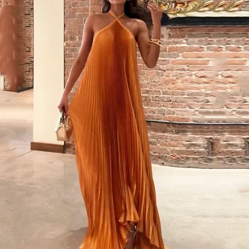 Close-up of the fine pleating and halter neckline detail on the orange Carmen maxi dress