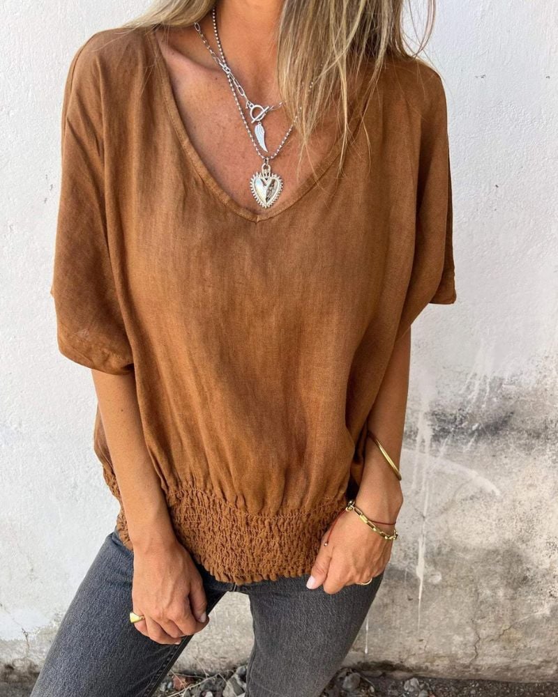 Model wearing a flowy relaxed summer top with V-neckline in brown, styled casually for warm weather