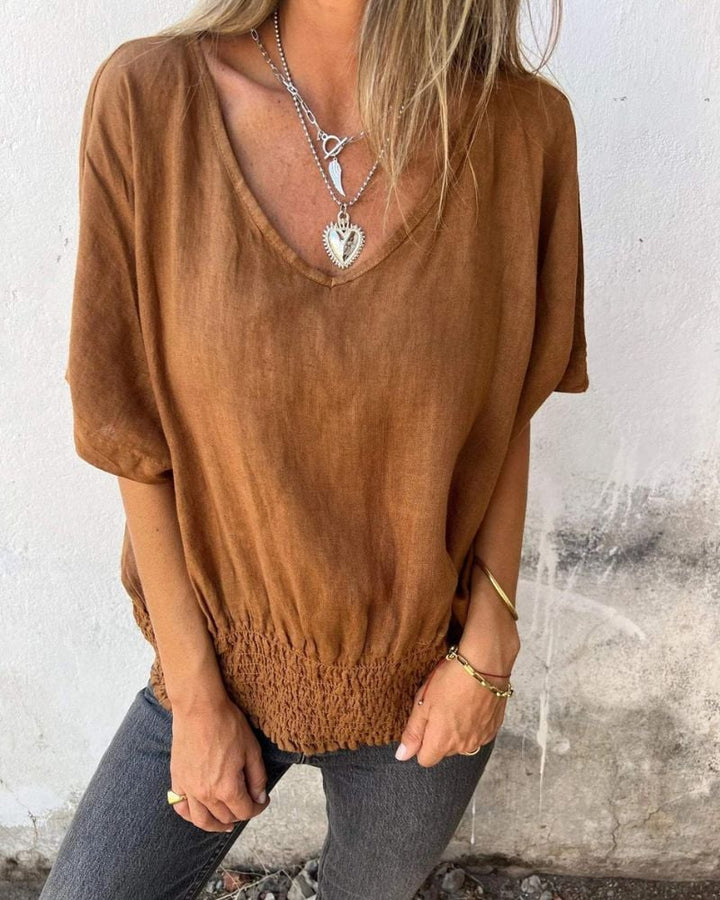Model wearing a flowy relaxed summer top with V-neckline in brown, styled casually for warm weather