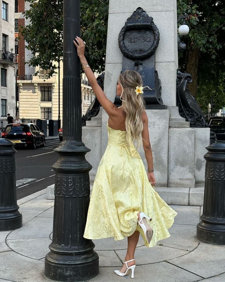 Woman in the Caroline white V-neck dress styled with heeled sandals and a clutch