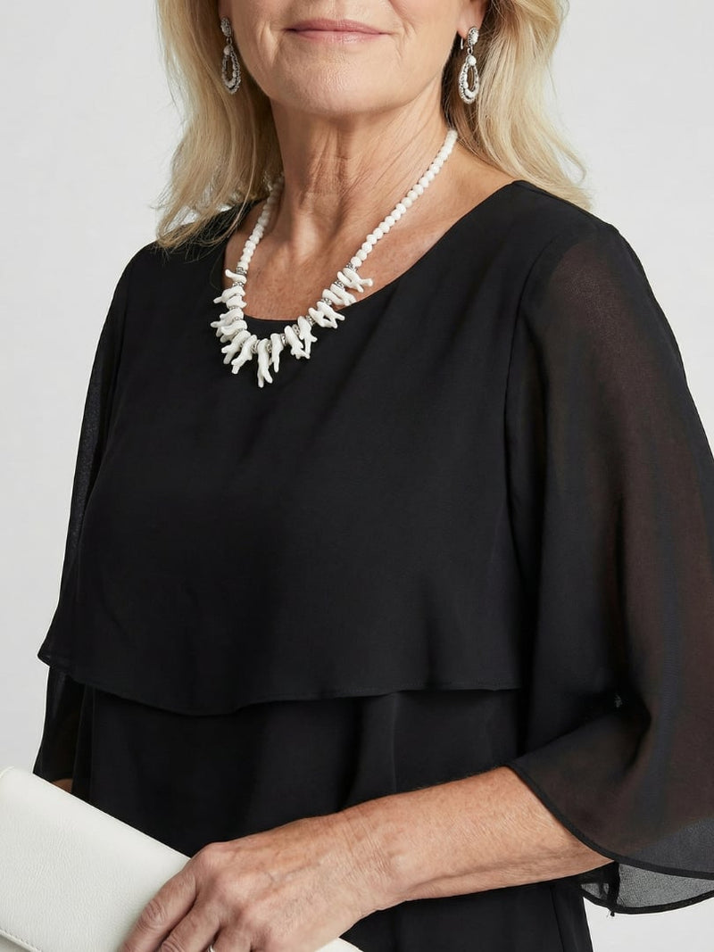 Side view of black tiered midi dress highlighting flowing silhouette and midi length
