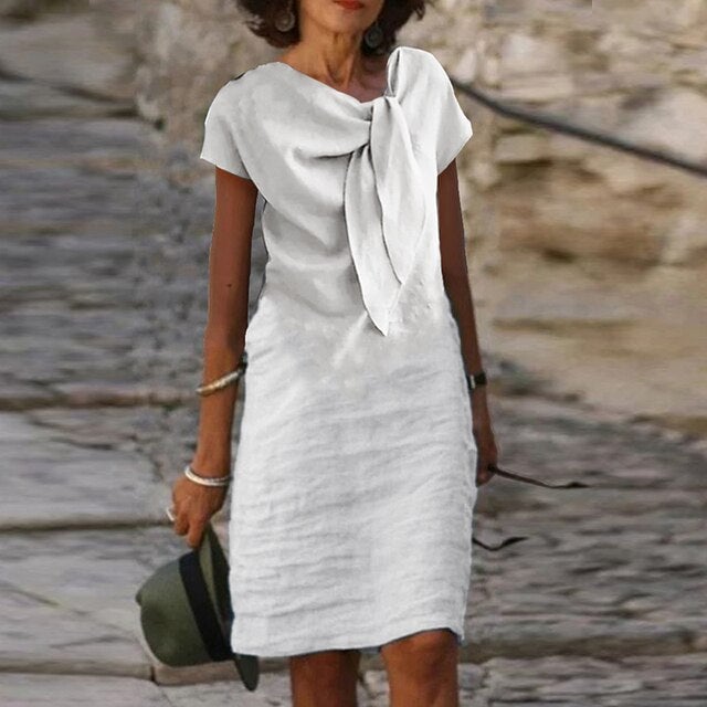 Front view of the Celeste midi dress in white with short sleeves and a feminine bow neckline detail