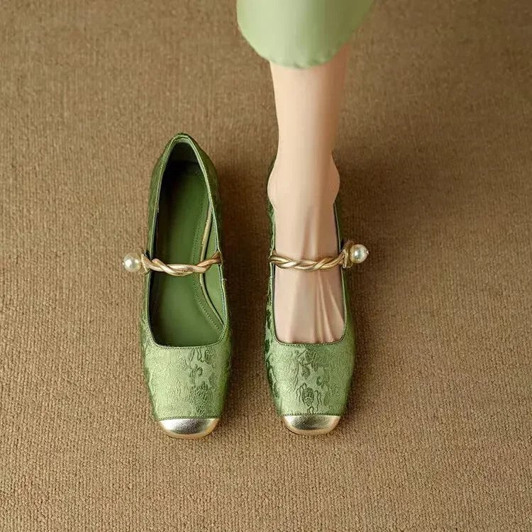 Close-up of pearl-embellished twisted strap and gold metallic square toe cap on sage green Celeste mary janes