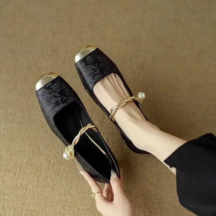 Close-up of pearl strap buckle and metallic toe cap on black Celeste mary jane heels