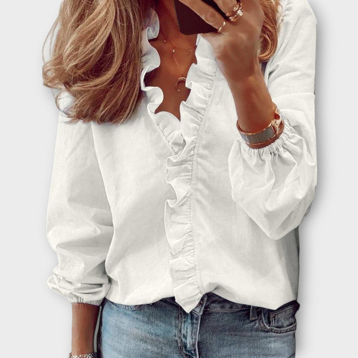 Woman wearing the Celeste white ruffle front V-neck long sleeve blouse with cascading center ruffle detail
