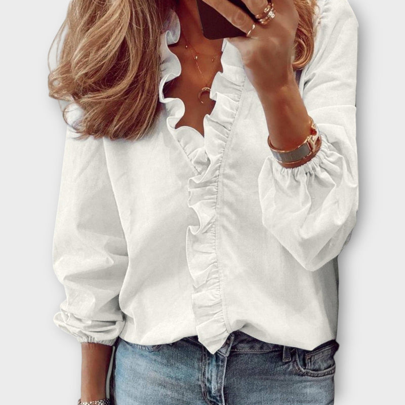 Woman wearing the Celeste white ruffle front V-neck long sleeve blouse with cascading center ruffle detail
