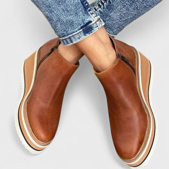 Chloe waterproof shoe in beige styled with slim trousers on a rainy day sidewalk