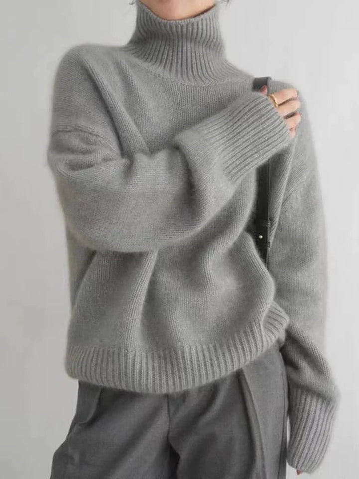 Close-up of a soft high collar sweater in grey showing knit texture and neckline detail