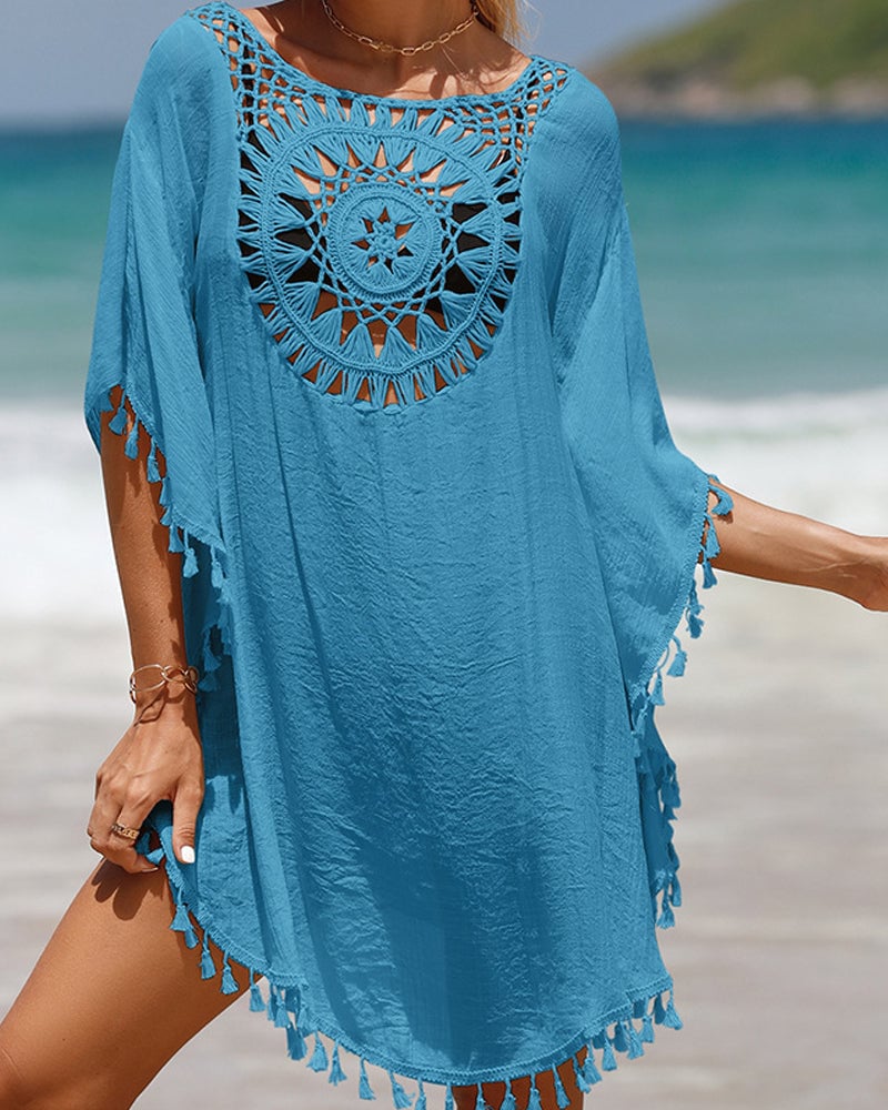 Blue boho beach cover-up with tassel accents worn by a woman walking on the sand