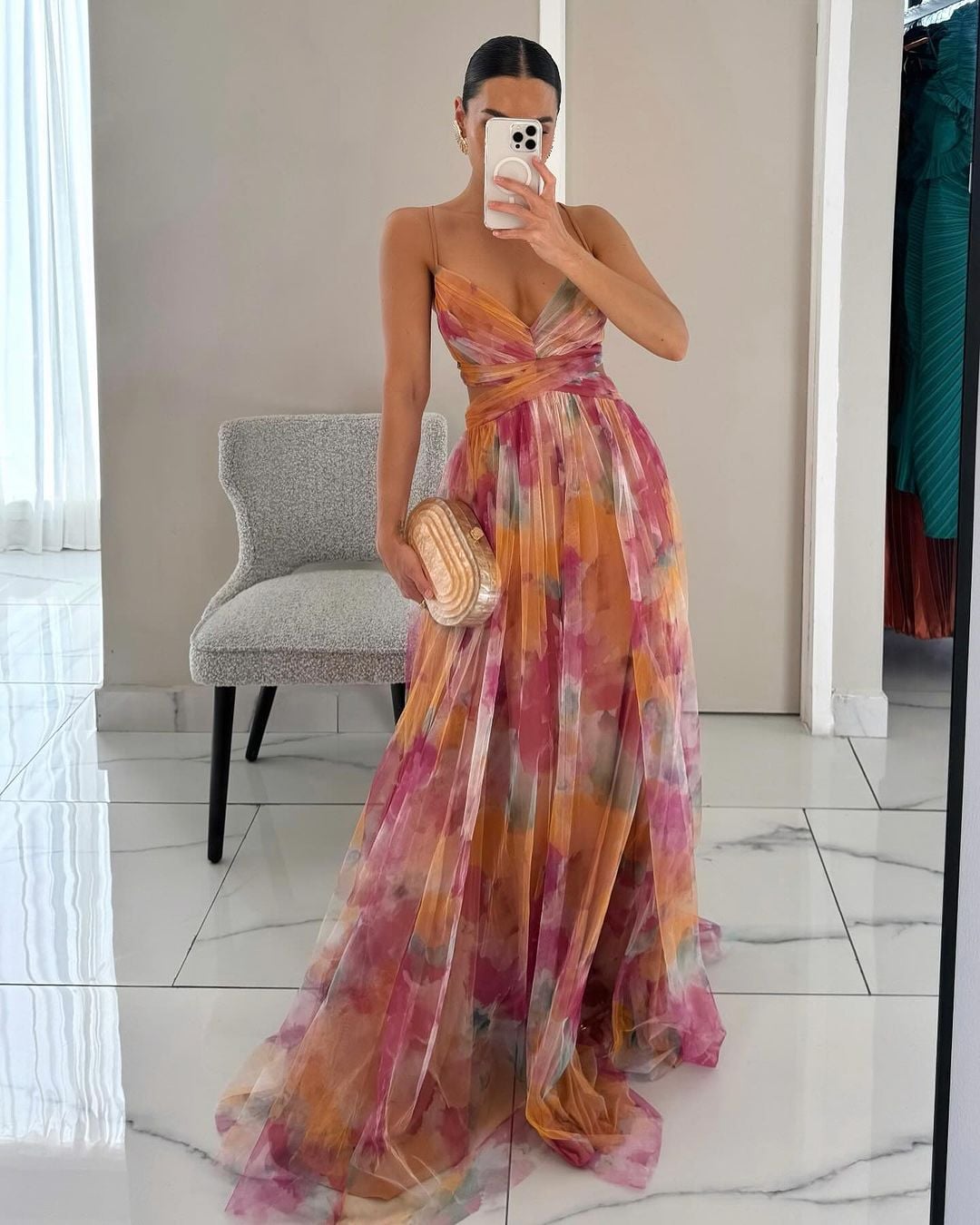 Woman wearing an orange floral print maxi dress with a flowing silhouette, standing outdoors in natural light