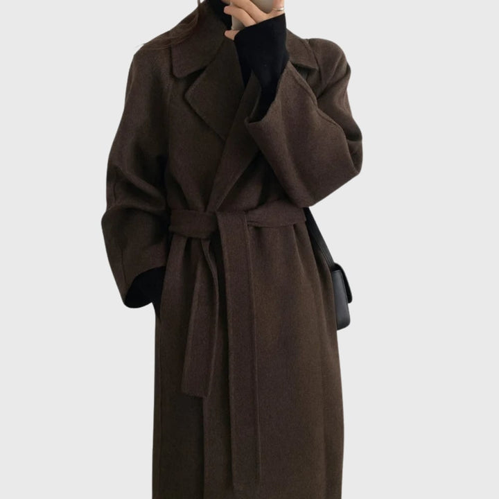 Woman wearing a belted overcoat in brown with a streamlined tailored fit, styled over trousers