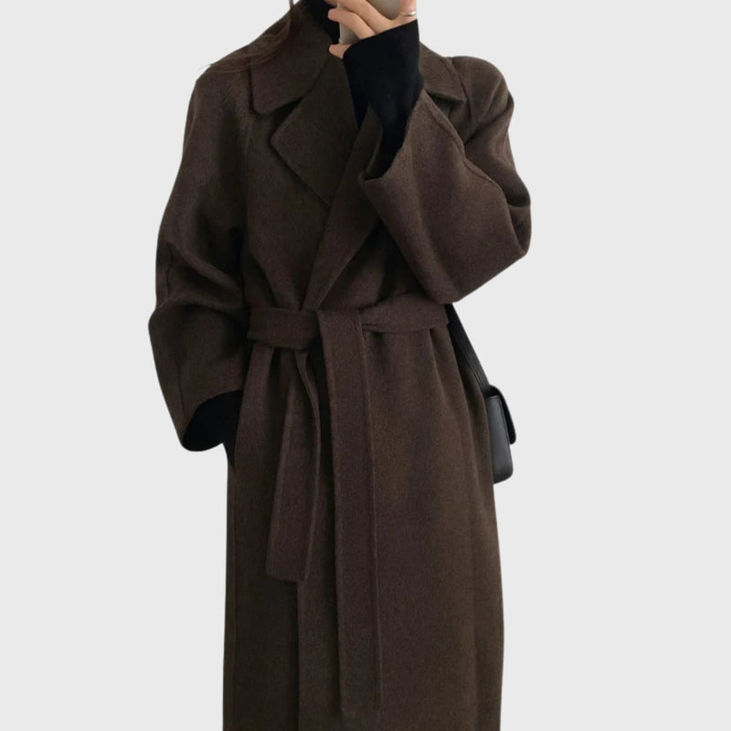 Woman wearing a belted overcoat in brown with a streamlined tailored fit, styled over trousers