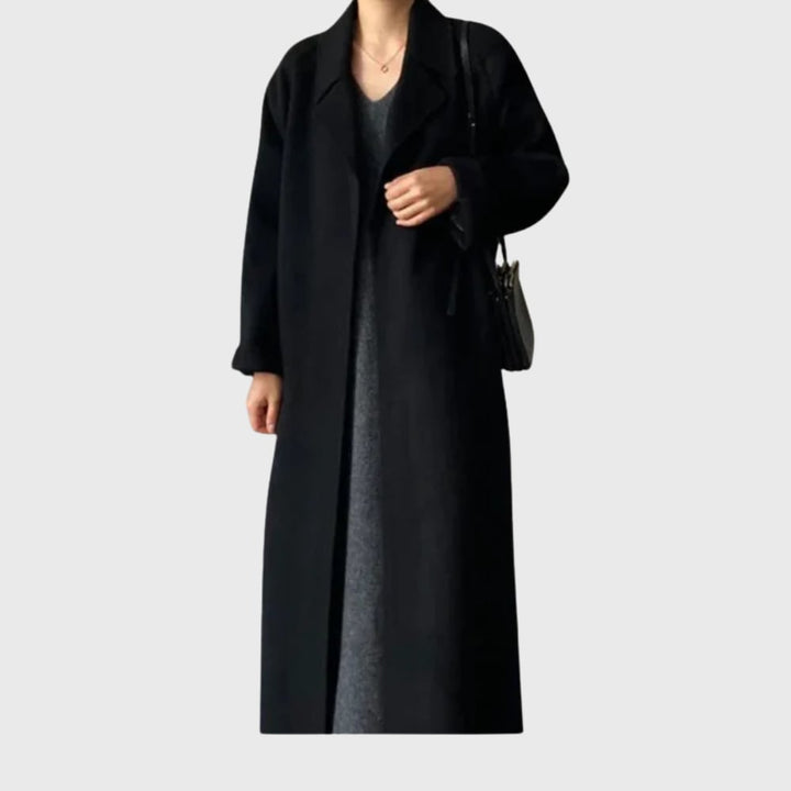 Woman in a black belted overcoat styled for an evening occasion with a polished look