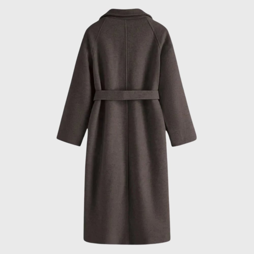 Model wearing the Florimay timeless belted overcoat in deep grey, walking outdoors in cold weather
