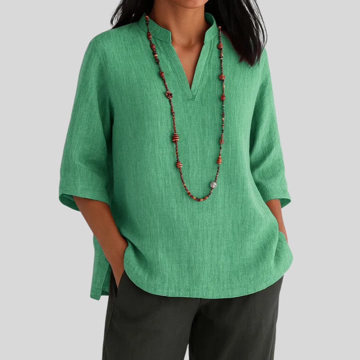 Woman wearing a relaxed-fit green blouse with a light, airy drape, styled for warm-weather wear